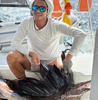 Angler holding a Sailfish on a catamaran - Catamaran Fishing Charters Seychelles