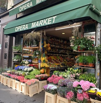 Devanture de l'épicerie Opera market avec des fleurs devant et des fruits et légumes et des vins 