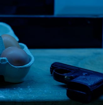 A still frame from the short film that consists of a box of eggs and a gun covered in flour