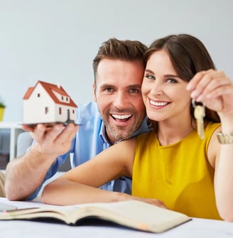 a man and woman holding keys to a house