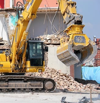 Pelle mécanique sur un chantier de démolition, avec des gravats, une structure partiellement démolie