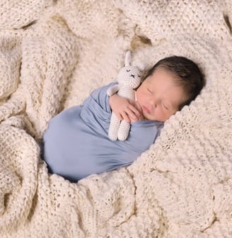 a baby boy is sleeping in a blanket