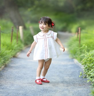 a little girl walking down a path with a red shoe