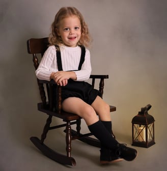 a little boy sitting in a rocking chair