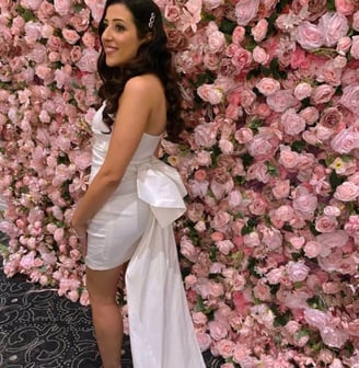 Bride to be in a white dress standing infront ouf our pink rose flower wall