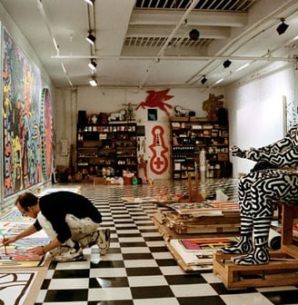 Ateliê vibrante de Keith Haring com paredes decoradas com grafite e arte pop.