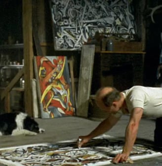 Ateliê de Jackson Pollock com telas no chão, mostrando sua técnica de dripping.