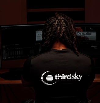 a man sitting at a desk with a computer monitor and a keyboard making film editing 
