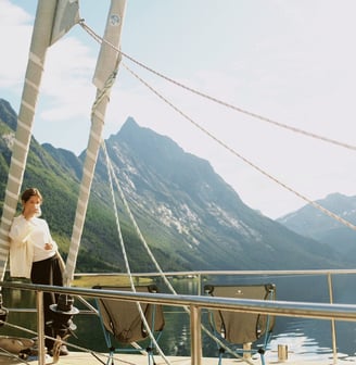 Georgina Amorós on sailboat deck with scenic mountain backdrop during summer sailing in Lofoten