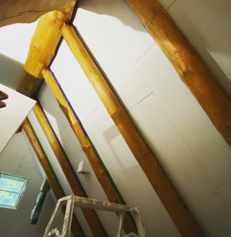 drywall ceiling install with exposed log beams