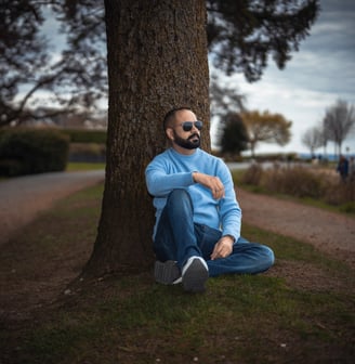 a man with a beard and sunglasses sitting on the ground