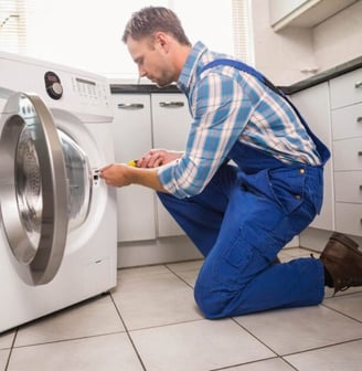 a man in overalls and overalls is fixing a washing machine