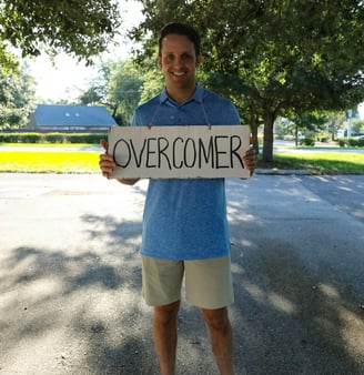 A transformed man holding a overcomer sign