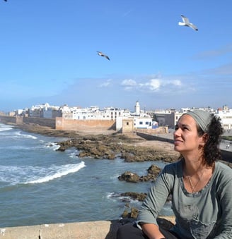 a woman sitting on a ledge looking out over the ocean beatriz alvarez