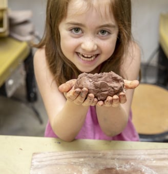 a young girl holding a clay creation
