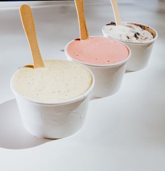 Tres tarrinas de helado de Flipa con sabores variados (vainilla, fresa y oreo) sobre mesa blanca.