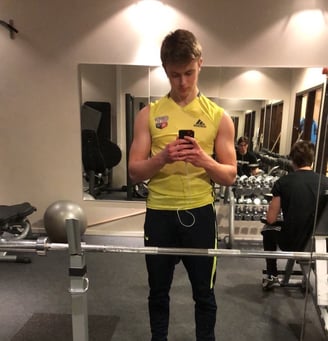a man in a yellow shirt is looking at his cell phone