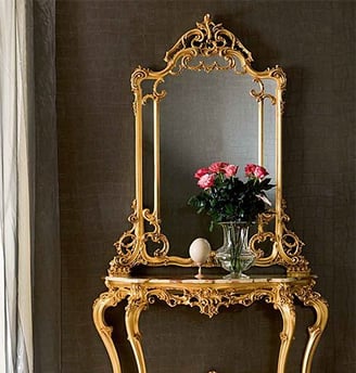 a console table with a mirror and a vase with flowers