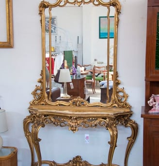 a gold console table with a gold frame and a mirror