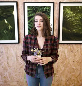 a woman standing in front of a wall with three framed pictures veste vintage en tweed