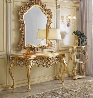 a gold cosole table with a mirror on the wall