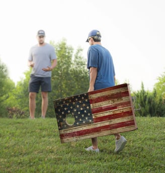 a man holding a corn hole board that is a flag
