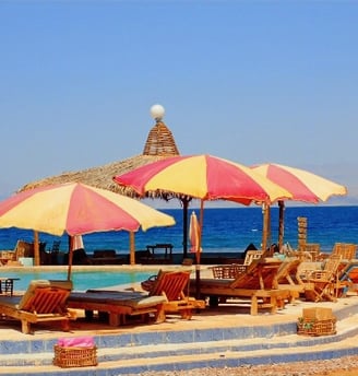 en strand med parasoller runt en pool i Egypten