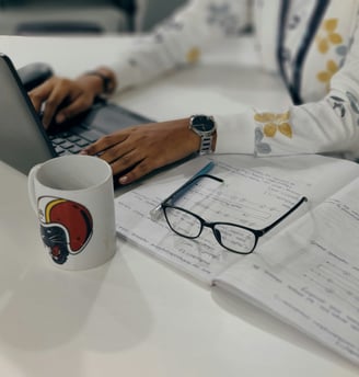a woman sitting at a desk with a laptop and a cup of coffee