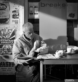 The street photography of Peter Pickering captures man reading the newspaper at a cafe