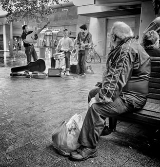 Composition in street photography by Peter Pickering shows man watching musicians perform