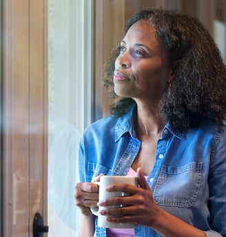 a woman holding a cup of coffee while looking out a window