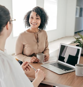 two women sitting at a table in an interview