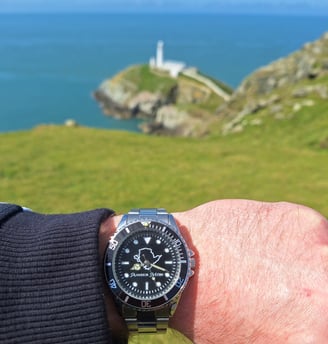 Amser Mon Anglesey black and white metal watch worn next to South Stack, Anglesey, Wales