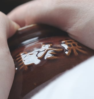 Clay pot with Chinese calligraphy held in hands