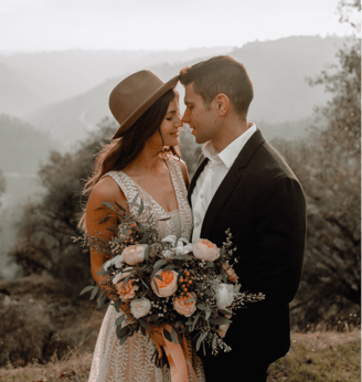 a young modern couple posing for there wedding pictures, the bride is wearing a hat