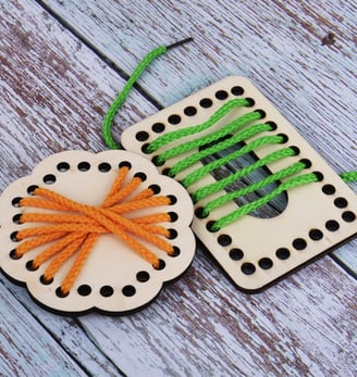 a pair of wooden buttons and string string tied to a wooden board