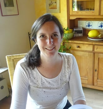a friendly smiling woman sitting at a table with a book