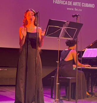 a woman in a black dress standing in front of a microphone and singing