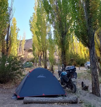 a motorcycle parked in a wooded area with a tent