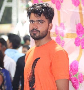 a man in a orange shirt and jeans standing in front of a wall