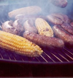 bratwurst on a grill with corn on the cob