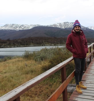 a man standing on a wooden bridge over looking a river