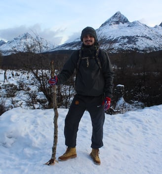 a man standing in the snow with a stick in his hand