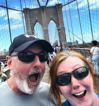 Two people looking happy on Brooklyn Bridge