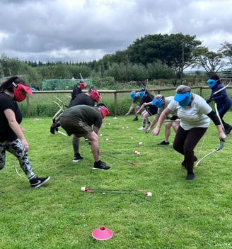 a group of people playing archery tag on a grassy field