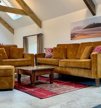 A room with ochre coloured soft seating and a colourful rug