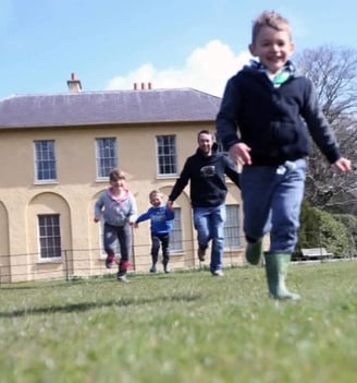 A family running in front of an historic house