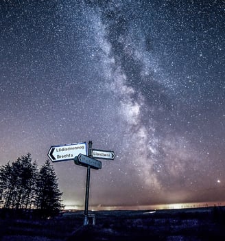 a street sign with a milky way like sky in the background