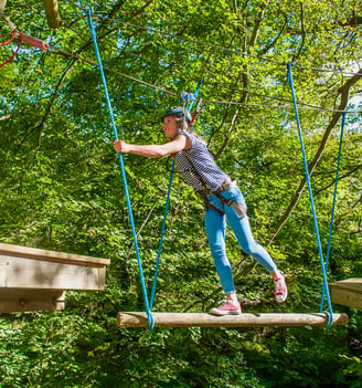 a woman in a helmet on a tied rope course