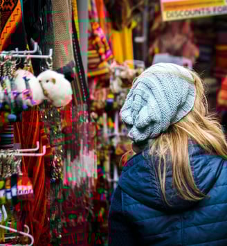 a woman in a blue jacket in a colorful market in Cusco Peru